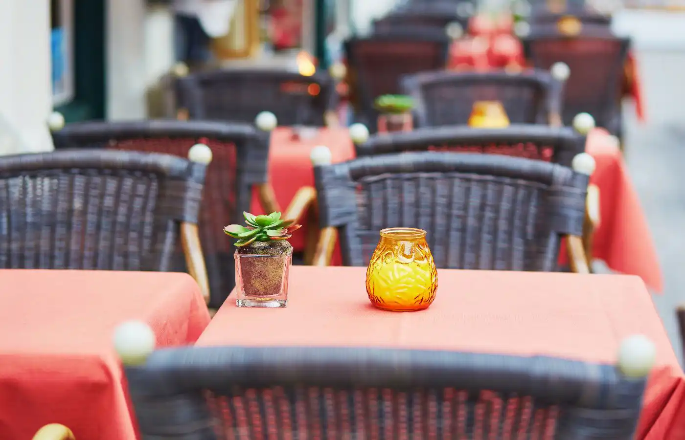 Terrasse extérieure d'un café avec des tables décorées de nappes rouges et de bougies, représentant un commerce local à Gosselies, Belgique.