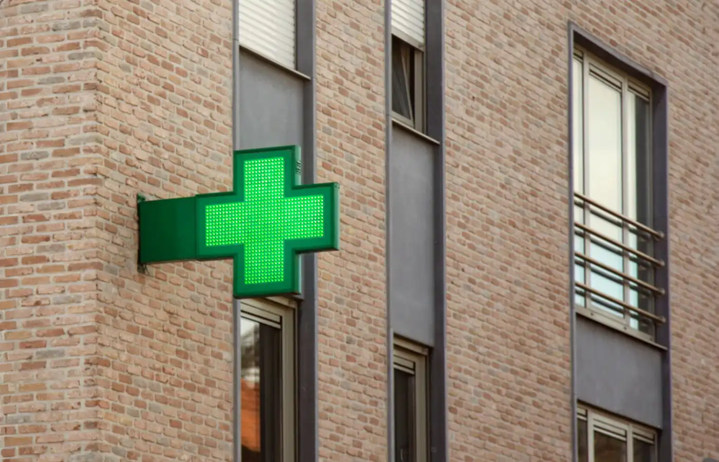 Enseigne lumineuse verte d'une pharmacie sur la façade d'un bâtiment moderne en briques à Gosselies.